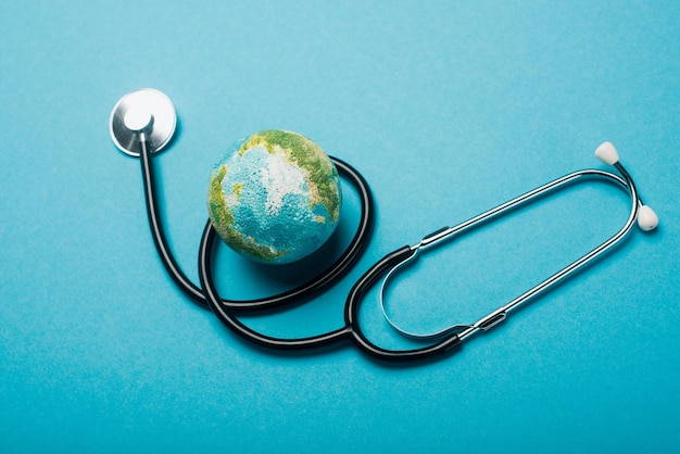 Globe and stethoscope on blue background, world health day concept