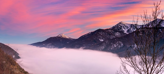 Glorious sunset in the italian Alps Beautiful sky over misty valley and snowcapped mountain peaks Winter in Piedmont Italy