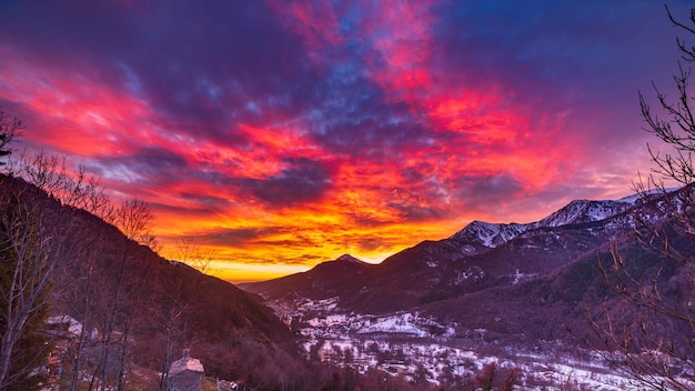 Glorious sunset in the italian Alps Beautiful sky over snowy valley idyllic village and snowcapped mountain peaks Winter in Piedmont Italy