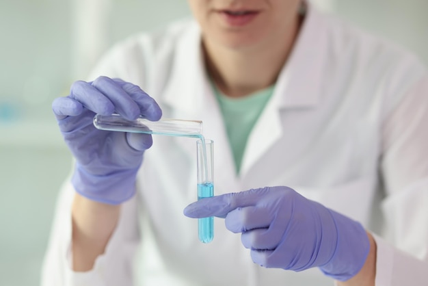 Gloved female scientist holds two test tubes of liquid in her hands closeup woman chemist in