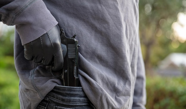 Gloved hand holding a pistol blur nature background