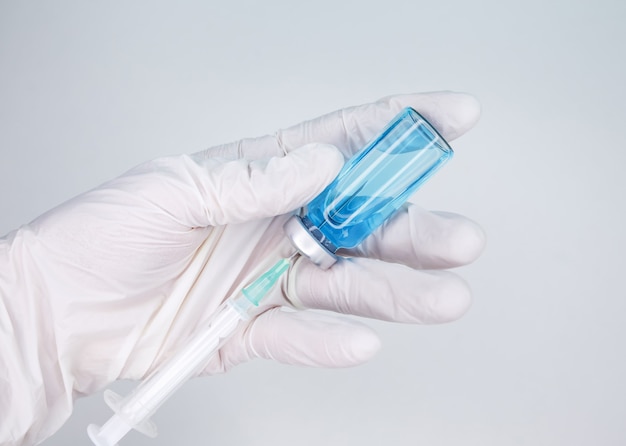 Gloved hand holding a syringe coronavirus covid  vaccine vial