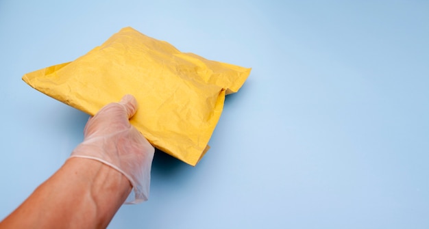 A gloved hand holds a craft package. Delivery of goods during quarantine of the coronavirus. Copy space