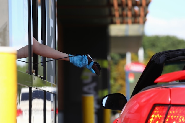 Gloved hand holds pos terminal and holds it out towards the car