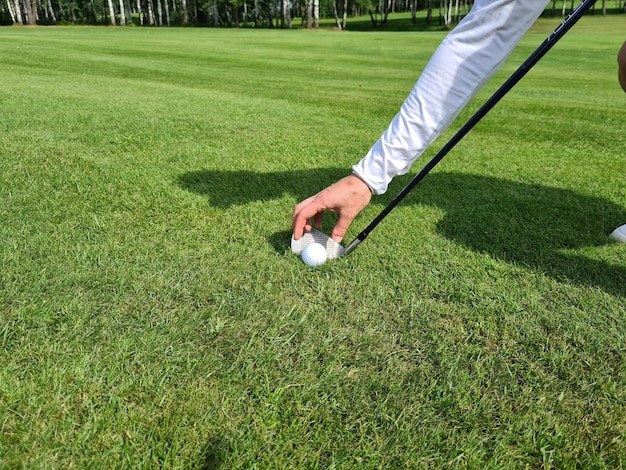 Gloved hand puts a golf ball on club