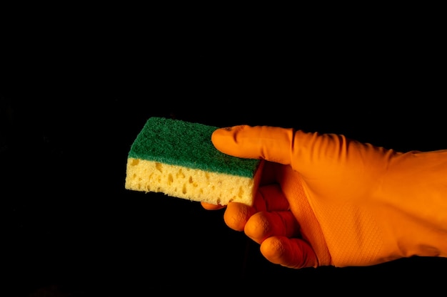 Photo gloved hand with washcloth on black background. the idea of cleaning premises