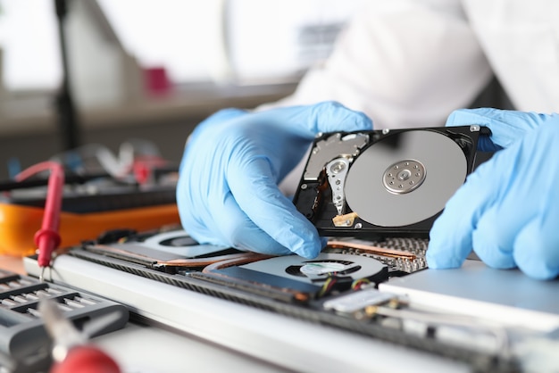 Gloved master holds a hard drive. Diagnostics and repair of computer equipment concept