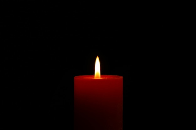 Glowing candle on black, space for text