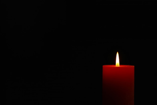 Glowing candle on black, space for text