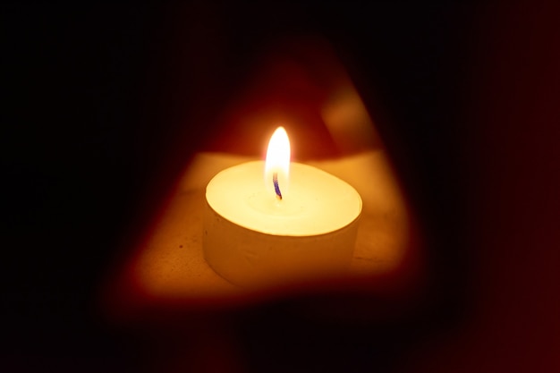 A glowing carved pumpkin with a candle inside in a dark background - halloween concept