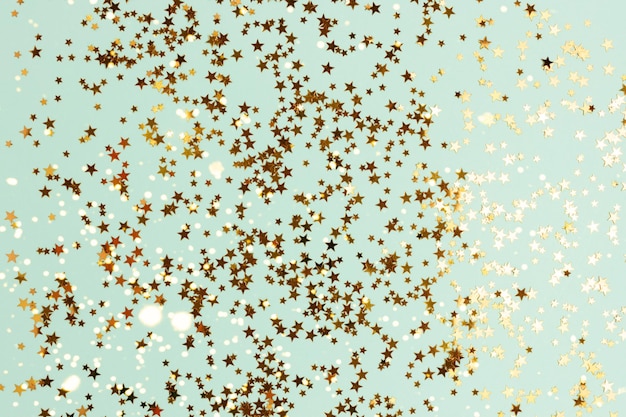 Glowing gold glittering stars confetti on a turquoise background