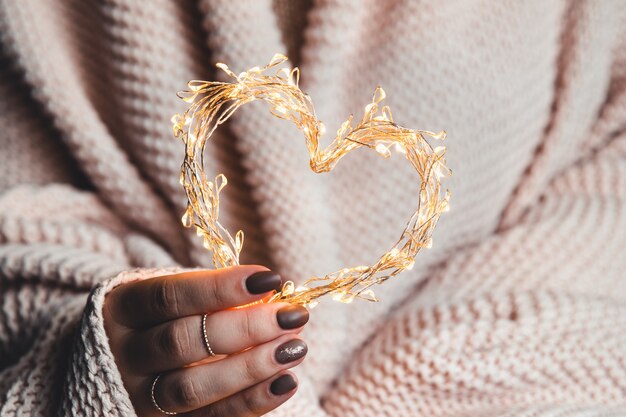 Glowing heart in the hands of a woman. Happy Valentine's day.