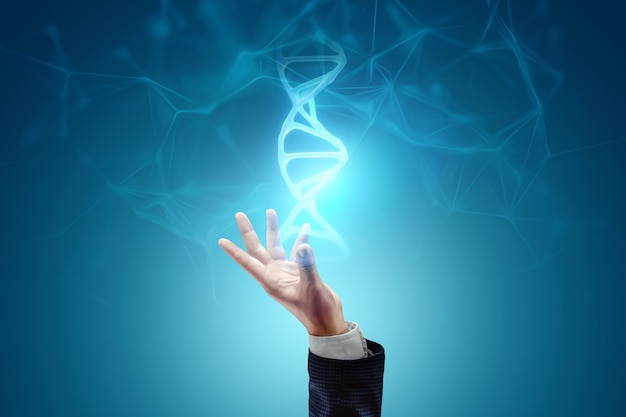 Glowing hologram of DNA molecule in the hand of a businessman on a blue background. Medical technology concept, science, biotechnology. Copy space.