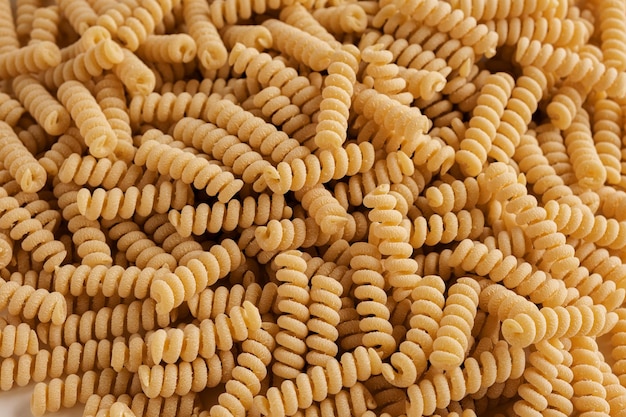 Gluten Free Cornmeal Pasta Wallpaper Spiral Raw Macaroni from Corn and Rice flour rotating on Turntable Close Up Top View Uncooked Pasta Spinning Full Frame Food Background Fusilli Bucati Corti