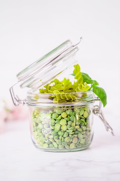 Gluten free green pea fusilli pasta and dry split light green peas on a white background, copy space