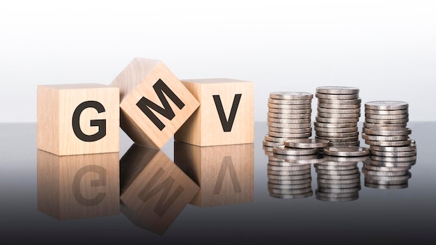 Gmv text is made up of letters on wooden cubes lying on a mirror surface