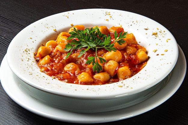 Gnocchi dish with tomato sauce and parsley on rustic wooden table