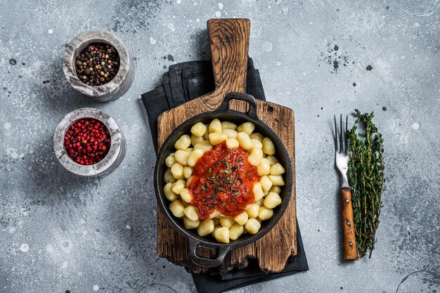 Gnocchi pasta with tomato sauce and parmesan. Gray background. Top view.