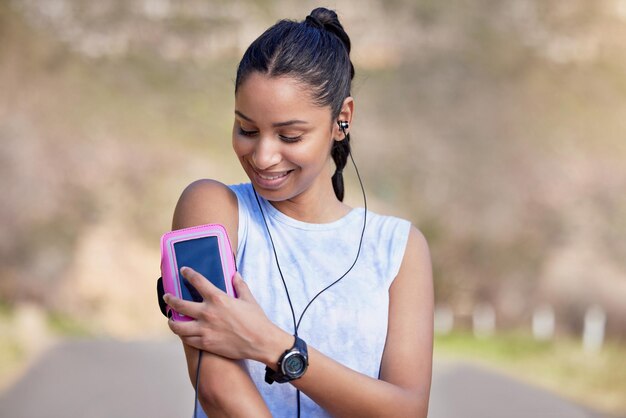 The go get em playlist. Cropped shot of an attractive young female athlete setting up her playlist before starting her outdoor run.