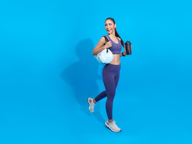 Go to training fitness Happy Asian sporty woman with bag on blue background