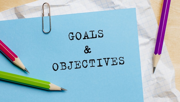 Photo goals objectives text written on a paper with pencils in office