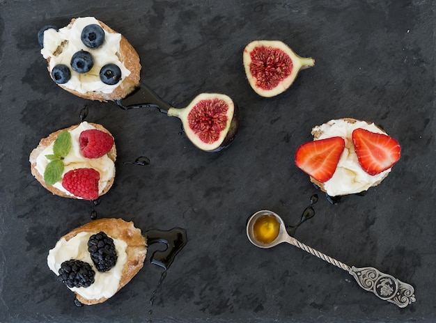 Goat cheese and berries mini-sandwitches on a dark surface