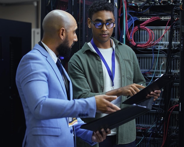 Going over the diagnostic report Cropped shot of two male IT support agents working together in a dark network server room