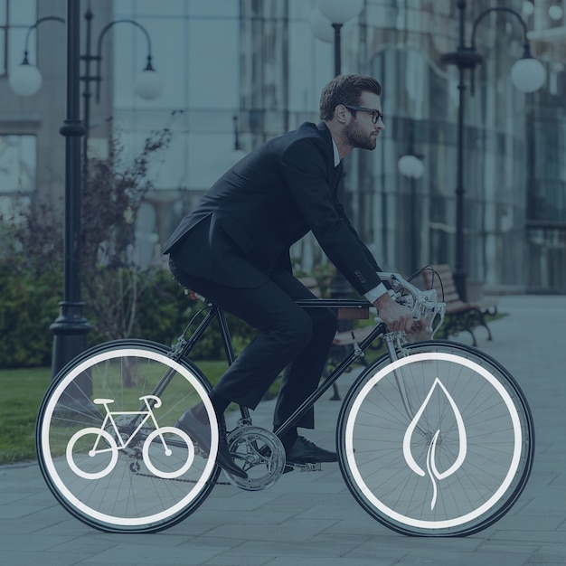 Photo going everywhere by his bike. side view of young businessman looking forward while riding on his bicycle