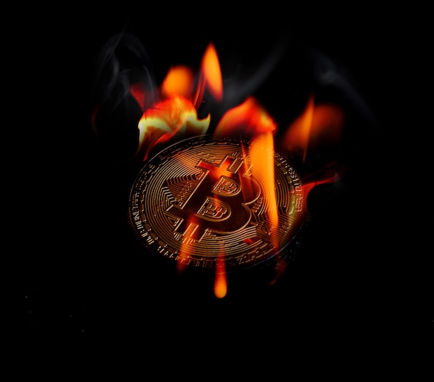 The gold bitcoin is on fire at a black background