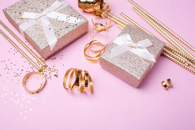 Gold boxes of gifts and gold tinsel for the holiday on a pink background Christmas Birthday