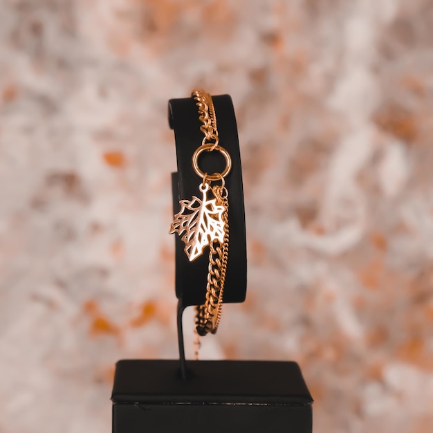 A gold bracelet with a leaf charm on it.