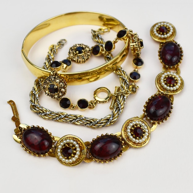 Gold bracelet with red and black stones on a white background close up