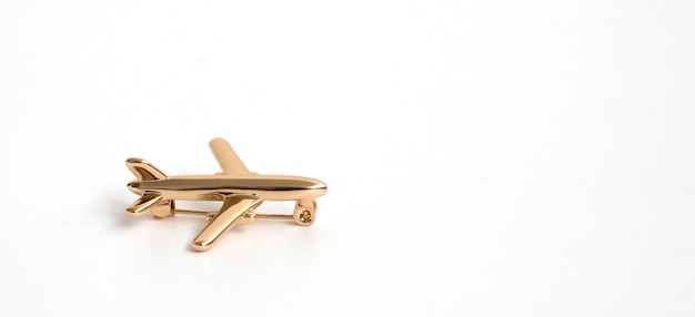 Gold brooch in the shape of an airplane on a white background.