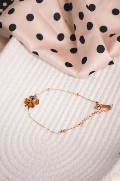 A gold chain with a flower on it sits on a bed.