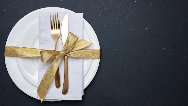 Photo gold cutlery on white set of dishes black background top view