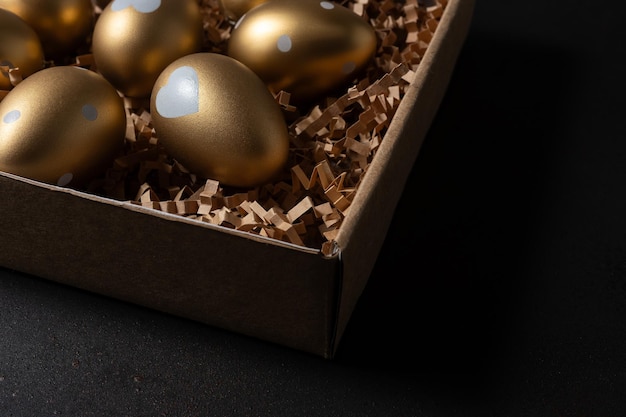 Gold eggs in paper box on black background