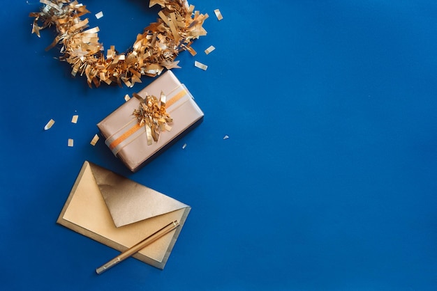 Gold Envelope Box Ribbon with wreath made of Christmas decoration on blue background