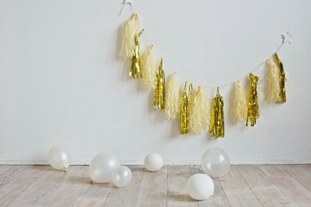 Gold garland on a white wall, balls on the floor