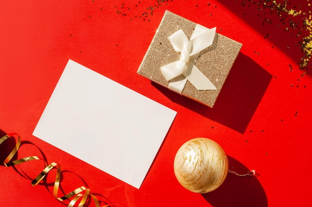 Gold gift and blank form for congratulations on a red background Flat lay style Christmas time