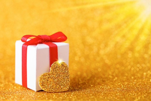 Gold heart and gift box on glitter gold background Valentines Day Copy space