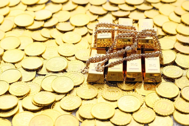 Gold necklaces and have gold bars with stack of coins money on yellow background Business investment and Saving money for prepare in future concept