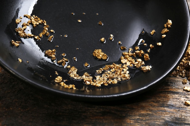 Gold nugget grains on black plate closeup