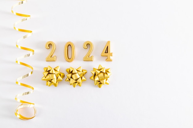 Gold numbers 2024 on a white fabric background with gold glitter decorations spiral and stars space for text postcard layout