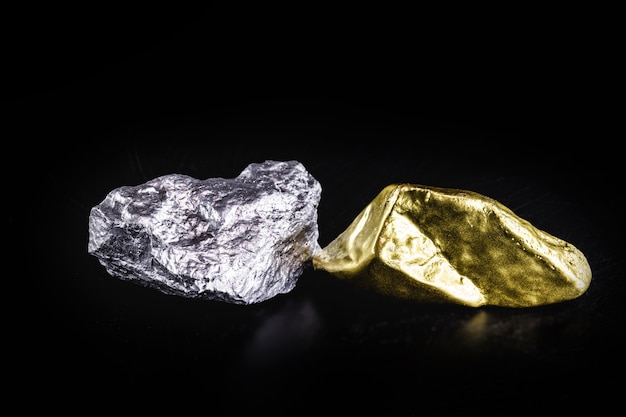 Gold ore and rough diamond on isolated black surface.