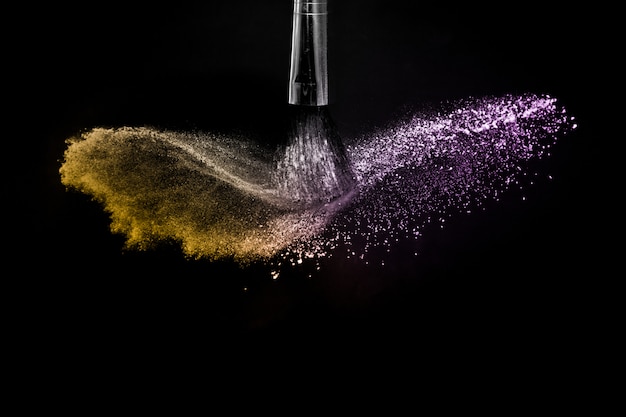 Gold and purple powder splash in black background