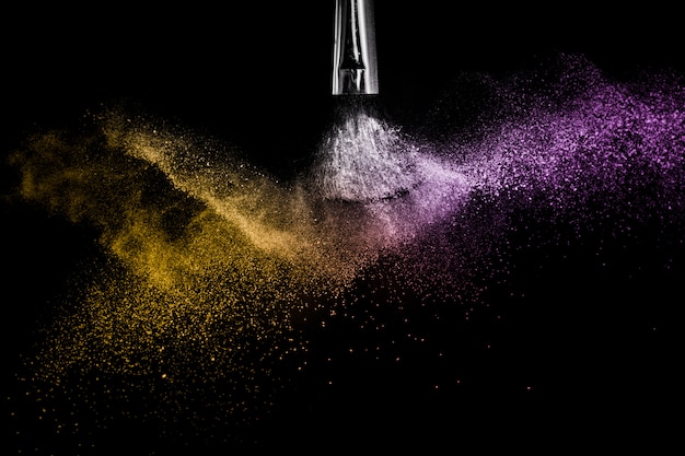 Gold and purple powder splash in black background