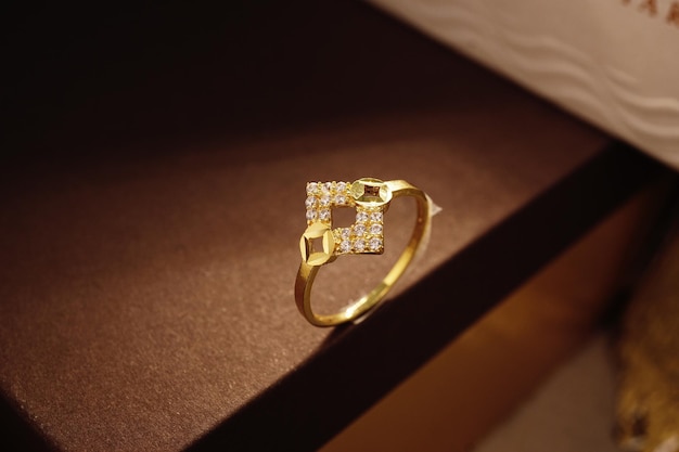 Gold ring cute with diamonds, cubic Zirconia, emeralds, and precious stones on background brown