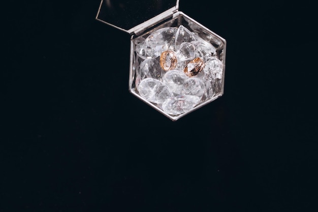 Gold rings frozen in ice on a black background with smoke and water drops