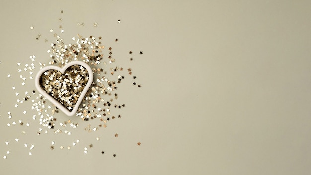 Gold  star sparkles form of heart on grey pastel trendy background for valentines day