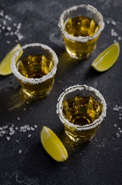 Gold tequila with lime and salt rim on dark stone